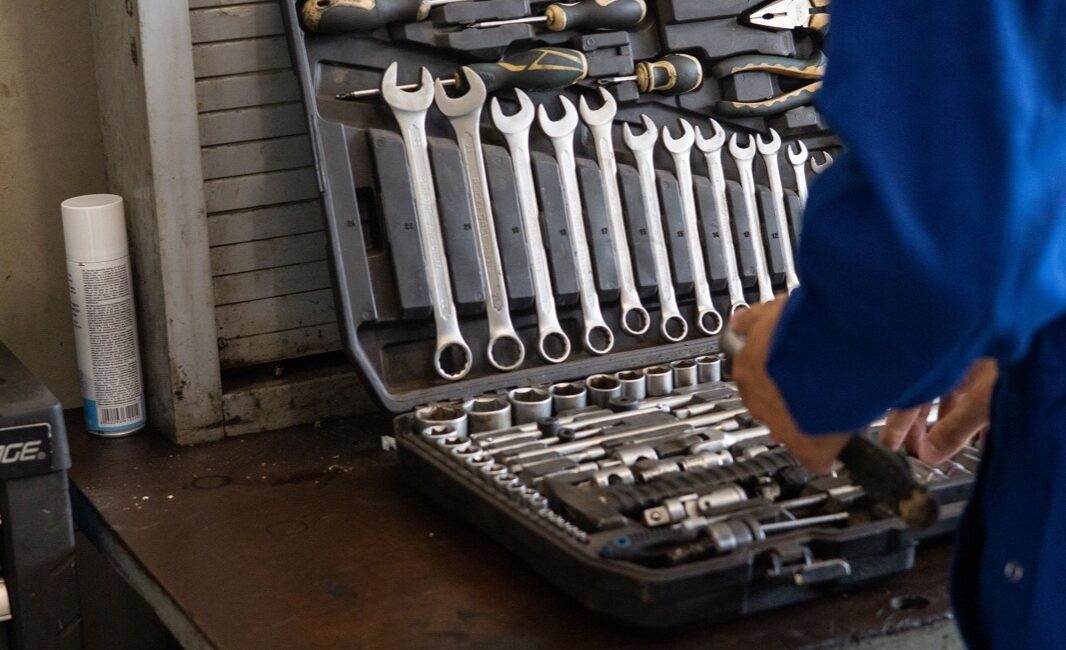 Mechanic in blue workwear inspecting a socket and tool set in a workshop